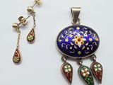 a close up of a necklace and earring on a white surface