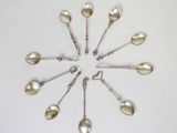six cuillères en argent disposées en cercle sur une surface blanche