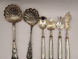 five spoons and a fork on a white surface