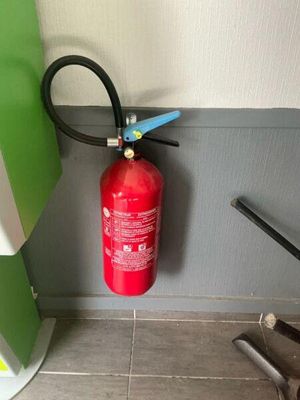 a fire extinguisor in the corner of a bathroom