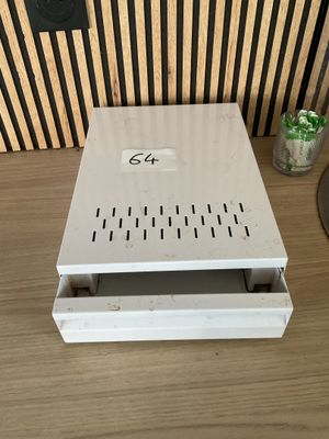 a small white box on a table with a green plant in it