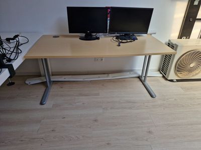 un bureau avec deux écrans et un ventilateur dans un coin