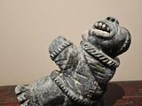 statue of a bear on a wooden table with a white wall in the background