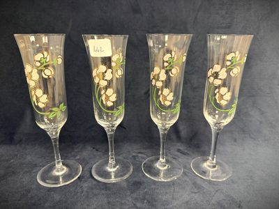 four wine glasses with flowers painted on them on a black background