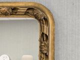 a mirror with a gold frame and a clock on it