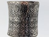 a close up of a silver cuff with intricate designs on it