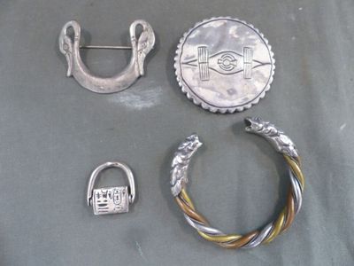 une broche en argent, une bague et deux autres objets posés sur une table