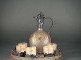 a silver and gold plate with candles and a pitcher