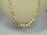 pearl necklace and earrings on a mannequin display on a white surface