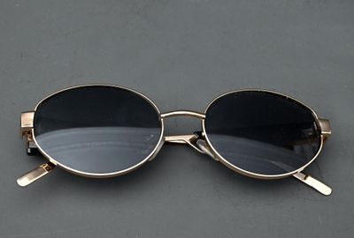 des lunettes de soleil posées sur une surface grise, sur fond noir