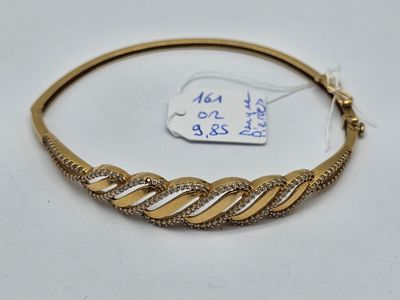 gros plan d'un bracelet en or sur une surface blanche
