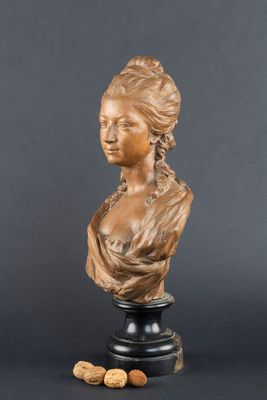 un buste en bronze représentant une femme aux cheveux longs, à côté de noix