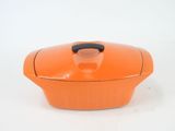 an orange casserole dish with a black handle on a white surface