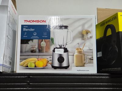un mixeur posé sur une étagère, à côté d'une boîte