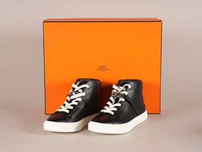 des baskets montantes noires et blanches devant une boîte orange