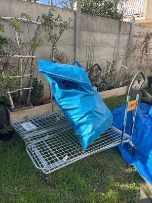 a cart that has a blue bag on it in the yard