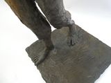 une statue représentant un homme tenant un couteau, perchée sur un rocher