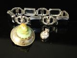 a silver bracelet with a green flower on it