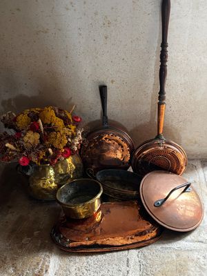 des casseroles et des poêles sont posées par terre à côté d'un vase de fleurs