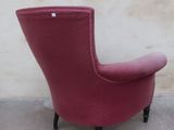 a red chair that is sitting in front of a wall