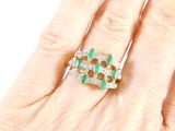 an image of a woman ' s hand with a diamond and emerald ring