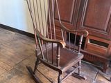 a rocking chair in the corner of a room next to a cabinet