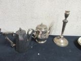 three silver teapots and two silver candlesticks on a table