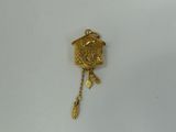 a close up of a small gold cuckoo clock on a white surface