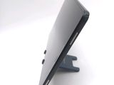 a black cell phone sitting on a stand on a white surface