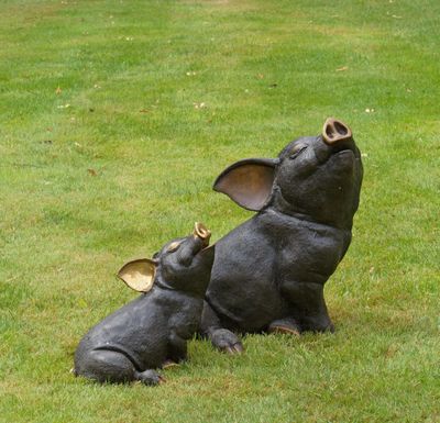 une statue représentant un cochon couché sur le dos dans l'herbe