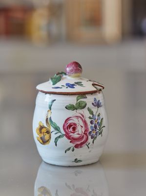un petit pot blanc orné de fleurs, posé sur une table