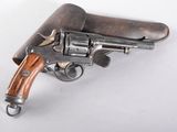 un vieux revolver avec une poignée en bois sur une surface blanche