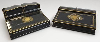 deux boîtes noires et dorées posées sur une surface blanche