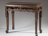 une vieille table en bois dont le plateau et les pieds sont sculptés