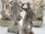 trois statues blanches représentant des femmes et un homme, posées sur un socle blanc