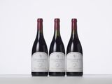 three bottles of red wine are lined up on a table