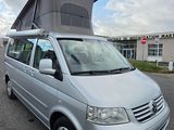 a silver van parked in a parking lot with a tent on top of it
