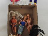 quatre poupées Barbie dans une boîte en carton posée sur une surface blanche