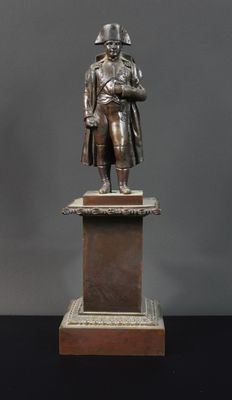 statue en bronze représentant un homme tenant un bébé dans ses bras, posée sur un socle
