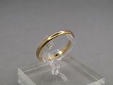 a gold ring on a clear stand on a gray surface