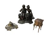 une statue représentant un homme assis sur un tabouret à côté d'une petite table