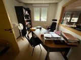 a desk with a chair and a fan in a room
