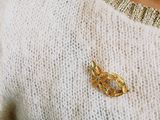 a woman wearing a white sweater with a gold brooch on it