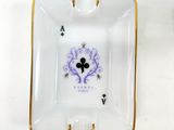 a white ashtray with a purple and black design on it