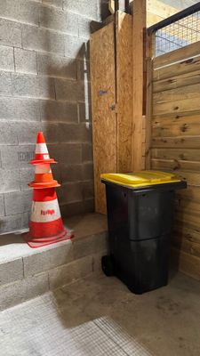 une poubelle noire posée à côté d'un cône jaune et blanc