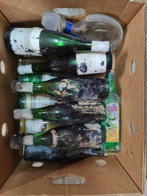 de nombreuses bouteilles vides dans un carton posé par terre