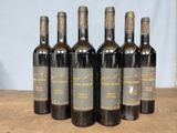 six bottles of wine are lined up on a wooden table