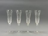 four crystal wine glasses are lined up on a gray surface