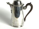 a silver coffee pot with a handle on a white surface