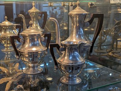de nombreux vases en argent posés sur une table en verre dans une vitrine